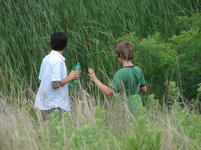 Two boys use all their sense to exam a tall grass prairie. 