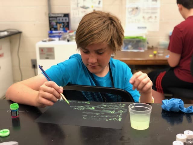 student using fluorescent solution to paint