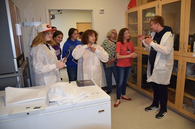 Students put on lab coats to get ready for microbiology lessons