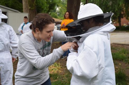 Student gets help donning bee keeper hat